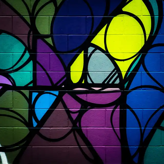 Close-up of a vivid geometric mural in blue, purple, green, and yellow