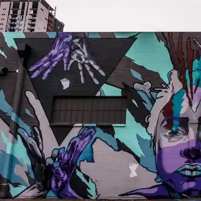 Street mural featuring expressive hands, birds, and a partial portrait