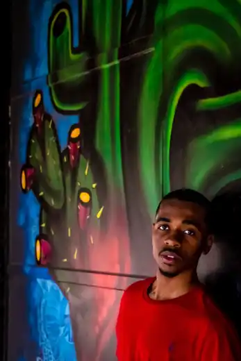 Portrait of a man in a red shirt against a colorful cactus mural