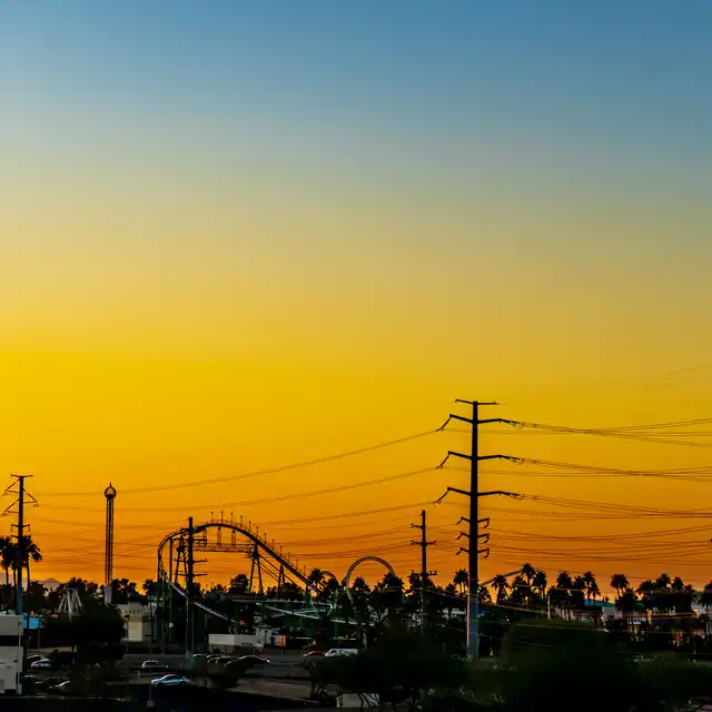 Golden sunset over Tempe with power lines, palm trees, and an amusement park silhouette